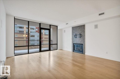 LIVING ROOM WITH WALL MOUNT FOR YOUR TV, BUILT IN SURROUND SPEAKERS, GAS FIREPLACE AND PATIO DOORS TO YOUR OUTDOOR LIVING SPACE - 503 10028 119 Street, Edmonton, AB - Indoor With Fireplace