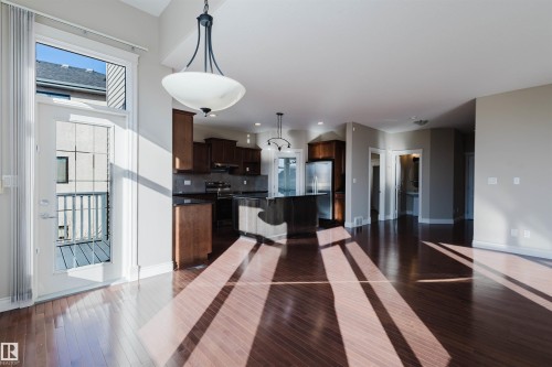 Kitchen with dark wood finish cabinetry, hanging light fixtures, a center island, and dark wood-type flooring - 3612 Mclay Court, Edmonton, AB - Indoor Photo Showing Kitchen