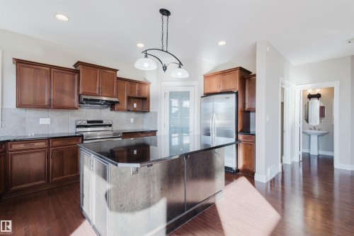 Kitchen featuring stainless steel appliances, a kitchen island, dark wood-style flooring, dark stone counters, and backsplash - 3612 Mclay Court, Edmonton, AB - Indoor Photo Showing Kitchen