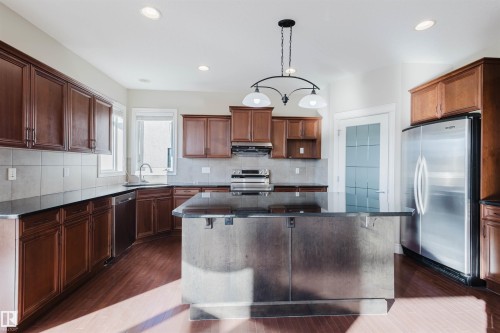 Kitchen featuring stainless steel appliances, a center island, dark wood-type flooring, and dark stone countertops - 3612 Mclay Court, Edmonton, AB - Indoor Photo Showing Kitchen