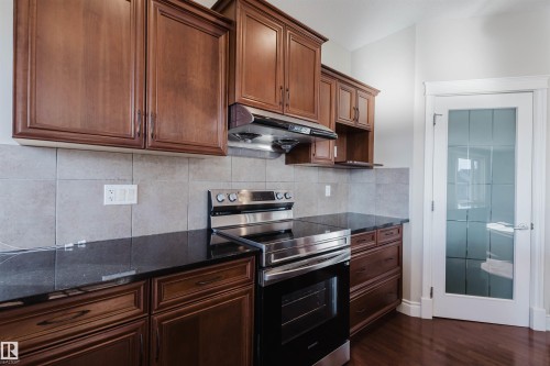 Kitchen with electric stove, tasteful backsplash, dark stone counters, and dark wood-style floors - 3612 Mclay Court, Edmonton, AB - Indoor Photo Showing Kitchen