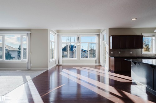 Kitchen with dark wood finish cabinetry, tasteful backsplash, light wood-type flooring, open floor plan, and decorative light fixtures - 3612 Mclay Court, Edmonton, AB - Indoor
