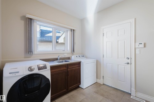 Laundry room featuring independent washer and dryer, cabinet space, and light tile patterned floors - 3612 Mclay Court, Edmonton, AB - Indoor Photo Showing Laundry Room
