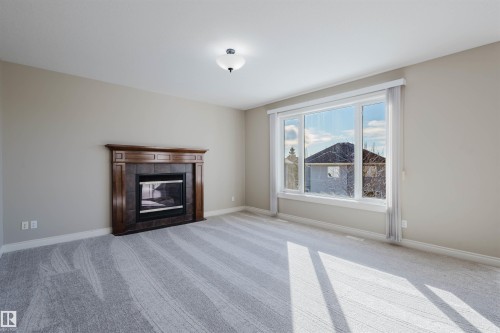 Unfurnished living room with light carpet and a fireplace - 3612 Mclay Court, Edmonton, AB - Indoor Photo Showing Living Room With Fireplace