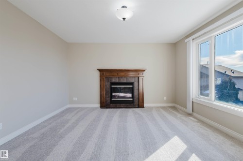 Unfurnished living room with light colored carpet and a fireplace - 3612 Mclay Court, Edmonton, AB - Indoor Photo Showing Living Room With Fireplace