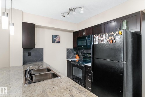 Kitchen with black appliances, backsplash, pendant lighting, and light stone countertops - 224 920 156 Street, Edmonton, AB - Indoor Photo Showing Kitchen With Double Sink