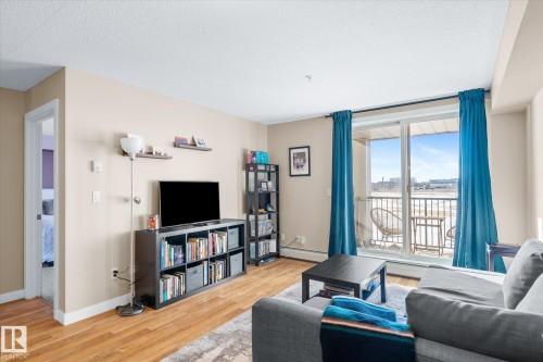 Living room with wood finished floors, baseboard heating, and a textured ceiling - 224 920 156 Street, Edmonton, AB - Indoor Photo Showing Living Room