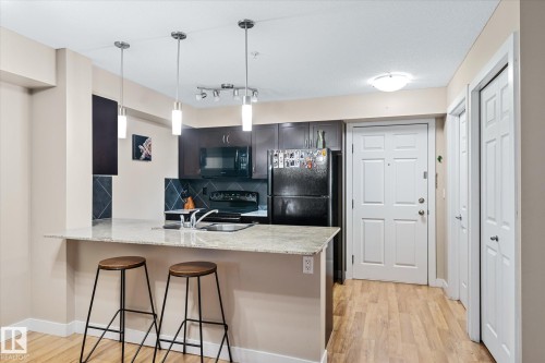 Kitchen with a kitchen bar, tasteful backsplash, a peninsula, black appliances, and light stone countertops - 224 920 156 Street, Edmonton, AB - Indoor Photo Showing Kitchen