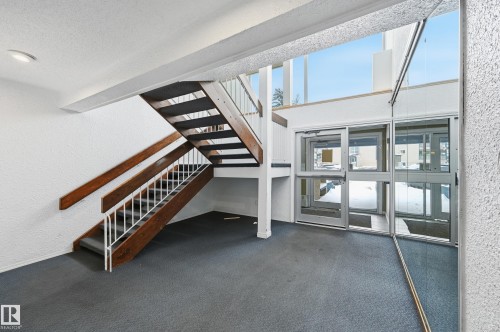 Unfurnished living room with dark carpet and a textured wall - 302 2624 Mill Woods Road E, Edmonton, AB - Indoor Photo Showing Other Room