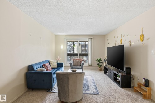 Carpeted living room featuring a textured ceiling and baseboards - 302 2624 Mill Woods Road E, Edmonton, AB - Indoor Photo Showing Living Room