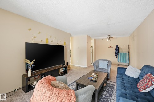 Living area with a textured ceiling, carpet, and ceiling fan - 302 2624 Mill Woods Road E, Edmonton, AB - Indoor Photo Showing Living Room