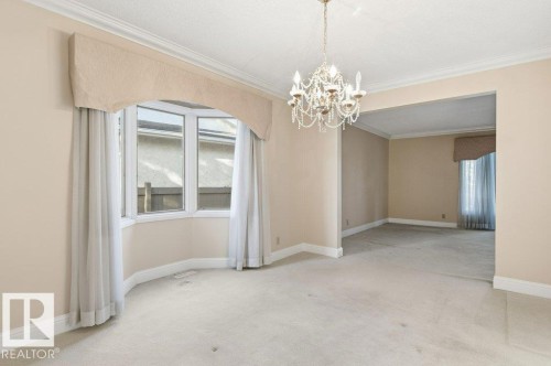 Unfurnished dining area with ornamental molding, carpet floors, and suspended lighting - 14335 47 Avenue, Edmonton, AB - Indoor Photo Showing Other Room