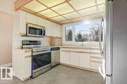 Kitchen featuring stainless steel appliances, light countertops, tasteful backsplash, and light floors - 