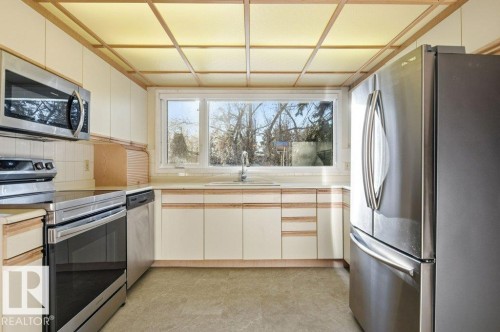 Kitchen featuring stainless steel appliances, light countertops, tasteful backsplash, and light flooring - 14335 47 Avenue, Edmonton, AB - Indoor Photo Showing Kitchen
