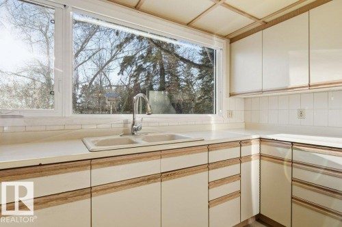 Kitchen with light countertops, tasteful backsplash, and dual tone cabinets - 14335 47 Avenue, Edmonton, AB - Indoor Photo Showing Kitchen With Double Sink