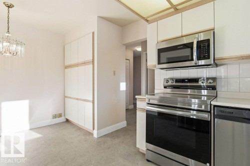 Kitchen with stainless steel appliances, light countertops, and hanging lights - 14335 47 Avenue, Edmonton, AB - Indoor Photo Showing Kitchen