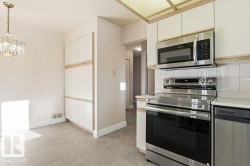 Kitchen with stainless steel appliances, light countertops, and hanging lights - 
