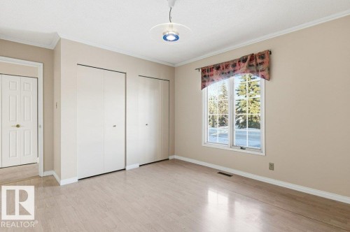 Unfurnished bedroom featuring multiple closets, crown molding, light wood-style floors, and a textured ceiling - 14335 47 Avenue, Edmonton, AB - Indoor Photo Showing Other Room