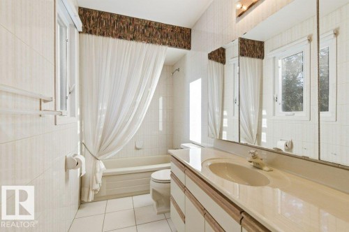 Bathroom with shower / bath combo with shower curtain, vanity, tile walls, and light tile patterned floors - 14335 47 Avenue, Edmonton, AB - Indoor Photo Showing Bathroom