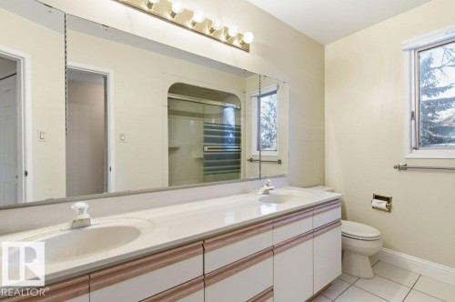 Bathroom featuring a shower stall, double vanity, and light tile patterned floors - 14335 47 Avenue, Edmonton, AB - Indoor Photo Showing Bathroom