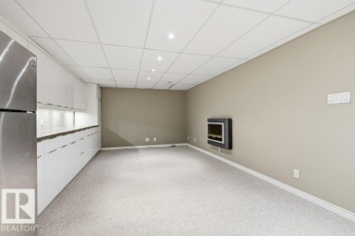 Finished basement with a paneled ceiling, freestanding refrigerator, and light carpet - 14335 47 Avenue, Edmonton, AB - Indoor Photo Showing Other Room