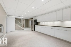 Kitchen with white cabinets, a paneled ceiling, light colored carpet, freestanding refrigerator, and recessed lighting - 