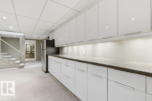Kitchen with a paneled ceiling, white cabinetry, light carpet, dark countertops, and freestanding refrigerator - 14335 47 Avenue, Edmonton, AB - Indoor