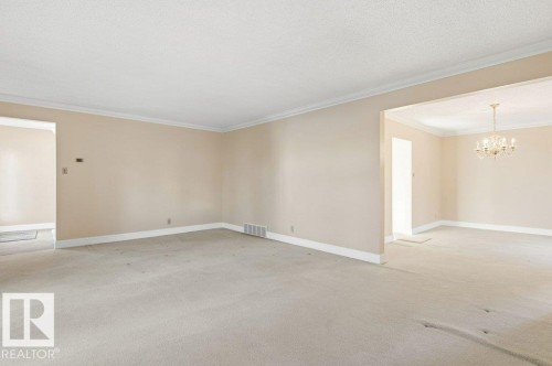 Unfurnished room with a chandelier, light carpet, ornamental molding, and a textured ceiling - 14335 47 Avenue, Edmonton, AB - Indoor Photo Showing Other Room