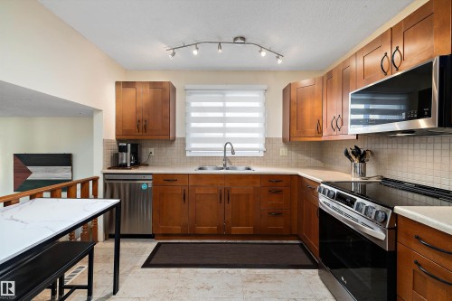 Kitchen featuring stainless steel appliances, wood finish cabinetry, and backsplash - 9804 156 Avenue, Edmonton, AB - Indoor Photo Showing Kitchen With Stainless Steel Kitchen With Double Sink