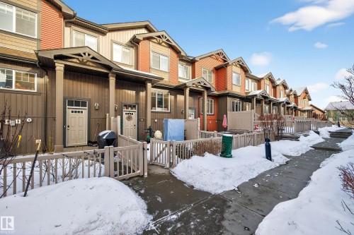 View of front of property with a residential view and a gate - 103 3305 Orchards Link Link, Edmonton, AB - Outdoor