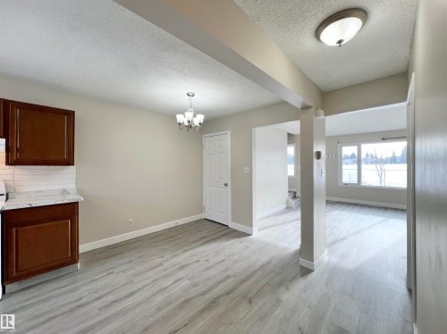 Unfurnished dining area featuring a textured ceiling, hanging lights, and light wood-type flooring - 11357 22 Avenue, Edmonton, AB - Indoor