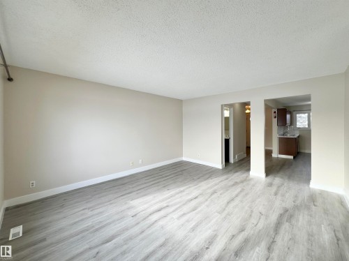 Unfurnished living room with a textured ceiling and light wood-type flooring - 11357 22 Avenue, Edmonton, AB - Indoor Photo Showing Other Room