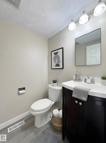 Half bath with vanity, a textured ceiling, and wood finished floors - 11357 22 Avenue, Edmonton, AB - Indoor Photo Showing Bathroom