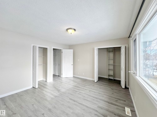Unfurnished bedroom with multiple closets, light wood-style floors, and a textured ceiling - 11357 22 Avenue, Edmonton, AB - Indoor Photo Showing Other Room