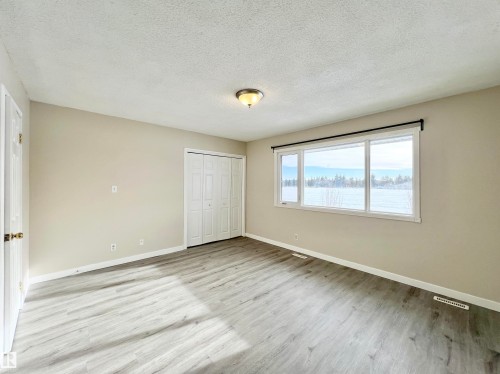 Unfurnished bedroom with light wood-style floors, a textured ceiling, and a closet - 11357 22 Avenue, Edmonton, AB - Indoor Photo Showing Other Room