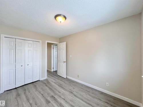 Unfurnished bedroom featuring a textured ceiling, a closet, and light wood-style floors - 11357 22 Avenue, Edmonton, AB - Indoor Photo Showing Other Room