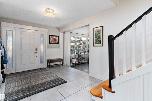 Entrance foyer featuring a textured ceiling, light tile patterned floors, stairway, a wainscoted wall, and a decorative wall - 317 Grand Meadow Crescent, Edmonton, AB - Indoor Photo Showing Other Room