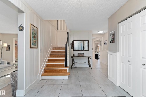 Staircase with a decorative wall, a textured ceiling, tile patterned flooring, and wainscoting - 317 Grand Meadow Crescent, Edmonton, AB - Indoor Photo Showing Other Room