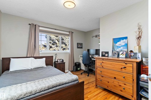 Bedroom featuring light wood-type flooring, a textured ceiling, and an office area - 317 Grand Meadow Crescent, Edmonton, AB - Indoor Photo Showing Bedroom