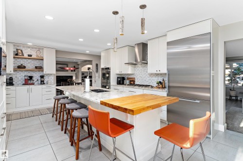 Kitchen with a kitchen island with sink, stainless steel appliances, light stone counters, white cabinetry, and a breakfast bar area - 317 Grand Meadow Crescent, Edmonton, AB - Indoor Photo Showing Kitchen With Upgraded Kitchen