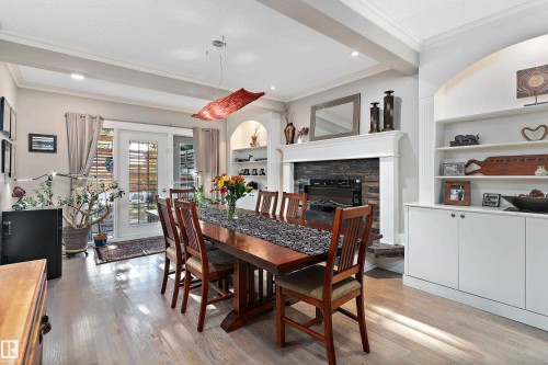 Dining space with light wood-style flooring, built in shelves, ornamental molding, a fireplace, and beamed ceiling - 317 Grand Meadow Crescent, Edmonton, AB - Indoor Photo Showing Dining Room With Fireplace