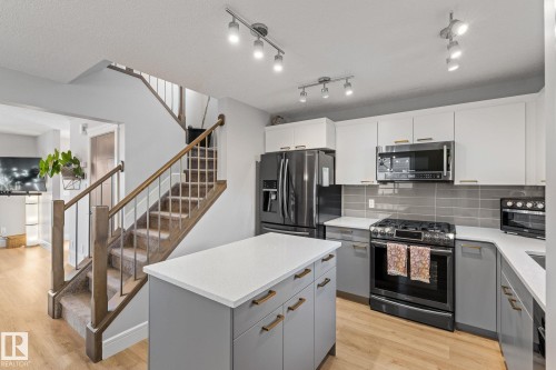 Dual tone kitchen with stainless steel appliances, gas stove, a kitchen island, light wood-type flooring, decorative backsplash, and dual tone cabinetry - 89 Hewitt Circle, Spruce Grove, AB - Indoor Photo Showing Kitchen With Upgraded Kitchen