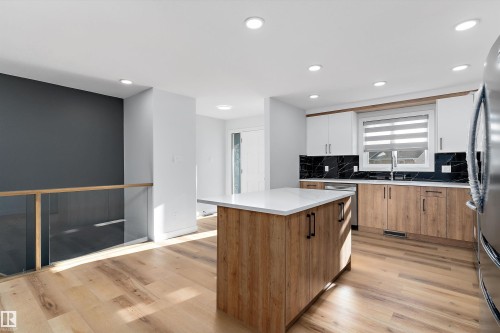 Kitchen featuring decorative backsplash, a kitchen island, dual tone cabinets, light wood-style flooring, and stainless steel appliances - 17116 81 Avenue, Edmonton, AB - Indoor Photo Showing Kitchen