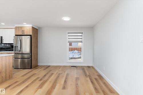 Dual tone kitchen featuring stainless steel fridge, light wood-type flooring, two tone cabinetry, decorative backsplash, and recessed lighting - 17116 81 Avenue, Edmonton, AB - Indoor Photo Showing Other Room