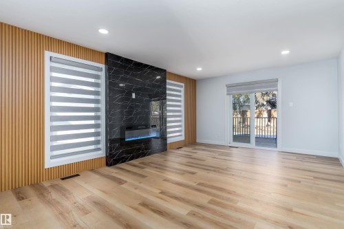 Unfurnished living room with light wood-style flooring, a premium fireplace, wine cooler, and recessed lighting - 17116 81 Avenue, Edmonton, AB - Indoor Photo Showing Living Room With Fireplace