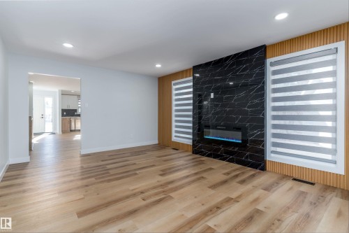 Unfurnished living room featuring healthy amount of natural light, light wood-style flooring, a high end fireplace, and recessed lighting - 17116 81 Avenue, Edmonton, AB - Indoor With Fireplace