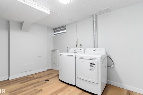 Laundry room featuring a textured ceiling, light wood finished floors, and independent washer and dryer - 17116 81 Avenue, Edmonton, AB - Indoor Photo Showing Laundry Room