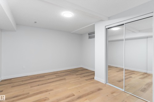 Unfurnished bedroom with a textured ceiling, a closet, and light wood finished floors - 17116 81 Avenue, Edmonton, AB - Indoor Photo Showing Other Room