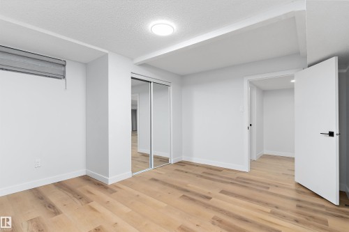 Unfurnished bedroom featuring light wood finished floors, a closet, and a textured ceiling - 17116 81 Avenue, Edmonton, AB - Indoor Photo Showing Other Room
