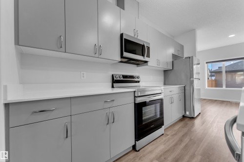 Kitchen with stainless steel appliances, light wood-style floors, gray cabinetry, modern cabinets, and recessed lighting - 1235 16 Avenue, Edmonton, AB - Indoor Photo Showing Kitchen